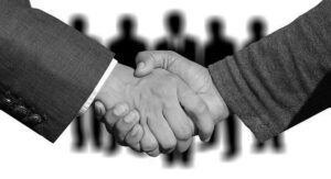 Zwei Aktionäre in Anzügen schütteln sich die Hände, um einen Pakt zu unterzeichnen