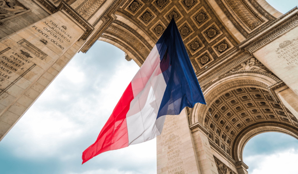 drapeau français au vent en dessus de l'arc de triomphe à Paris